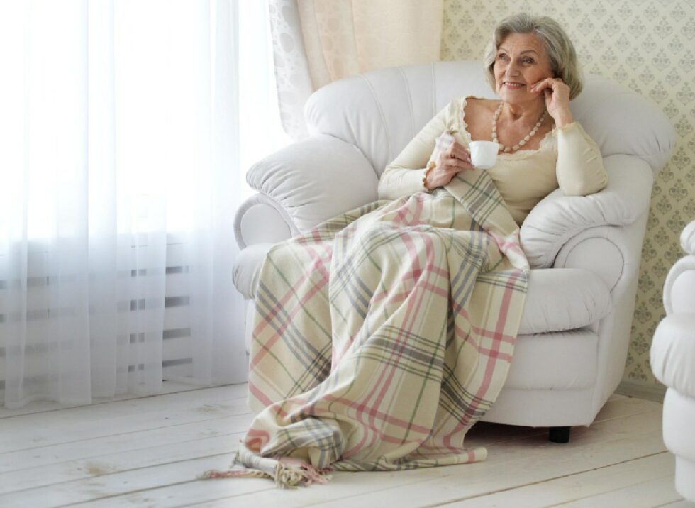 Seniorin mit Kuscheldecke im Sessel