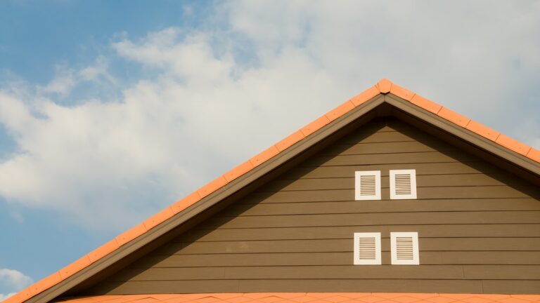 Giebel eines Wohnhauses mit Ziegeldach vor blauem Himmel mit Wolken