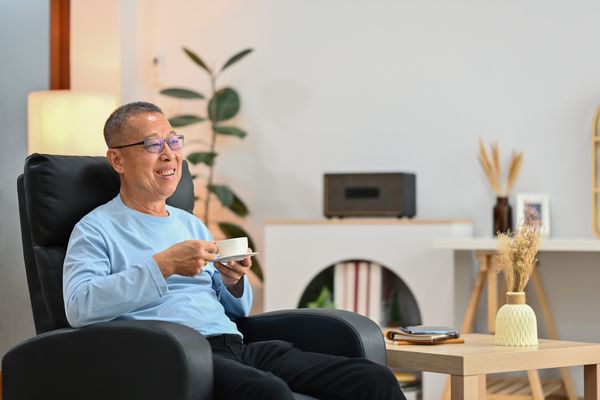 Aelterer Mann mit Tasse im Sessel