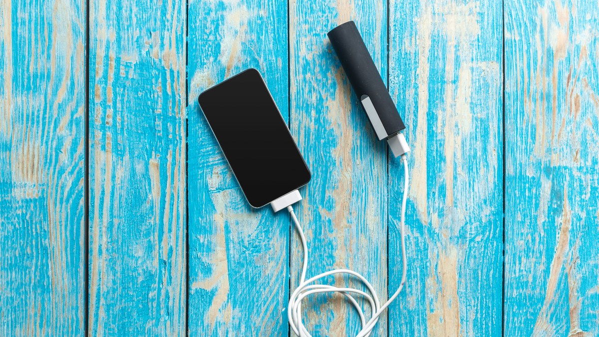 Smartphone wird ueber ein Kabel an einer Powerbank geladen