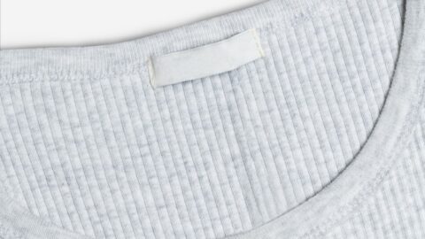 Grauer Pullover von innen mit leerem weissem Etikett im Nacken