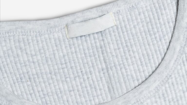 Grauer Pullover von innen mit leerem weissem Etikett im Nacken
